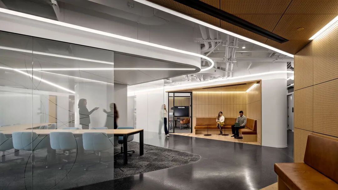 A room with a large glass wall and a couple people sitting at a table.